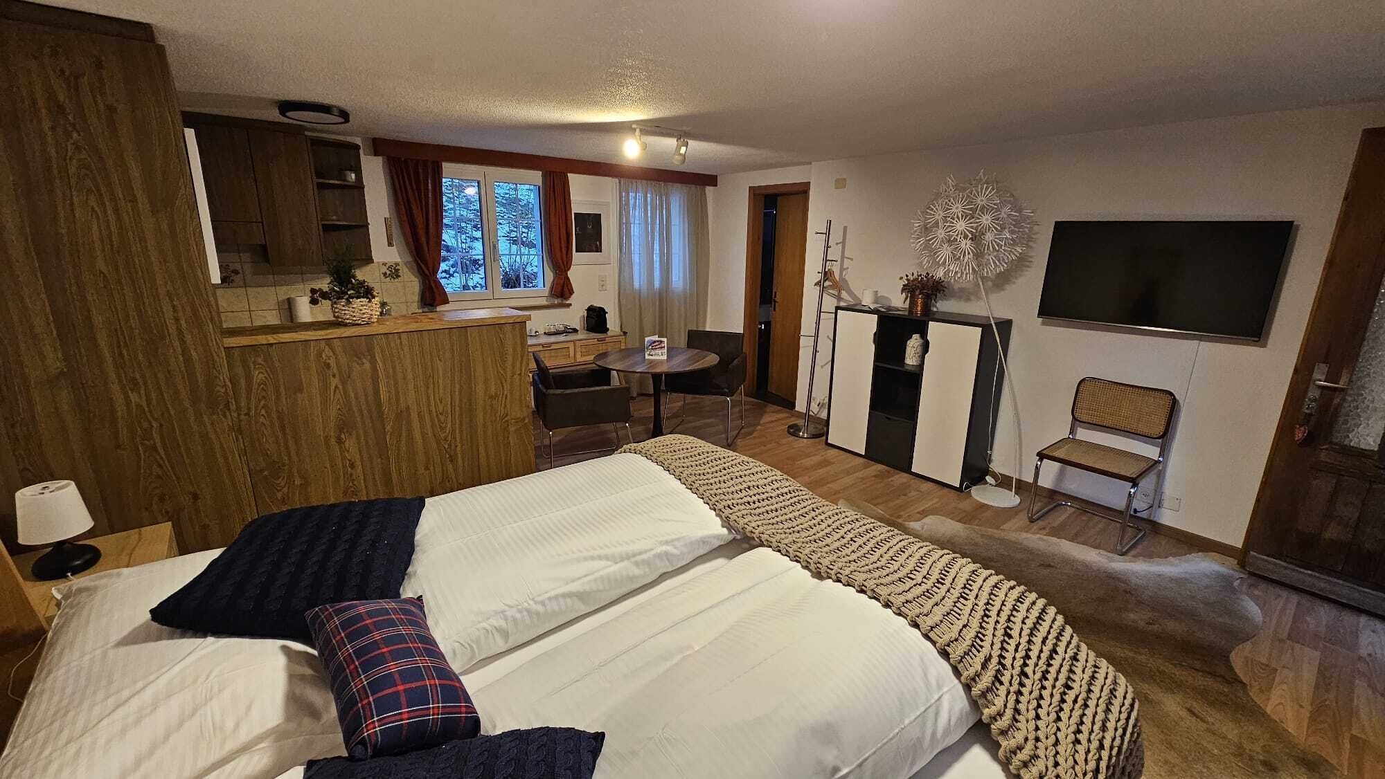 Una habitación de hotel con una cama grande, un escritorio, una silla, un televisor y una ventana con cortinas.