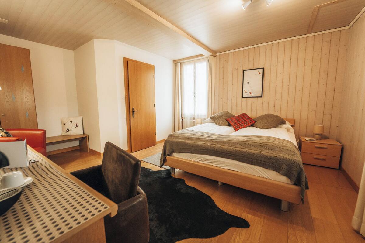 Un dormitorio con una cama de madera, un escritorio y una silla.
