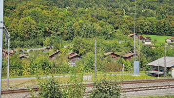 A rural village with houses, a railway track, and a mountain in the background.