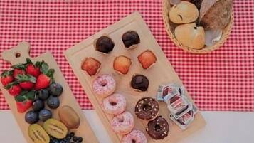 Ein Frühstücksbuffet mit Gebäck, Früchten und Kaffee auf einer karierten Tischdecke.