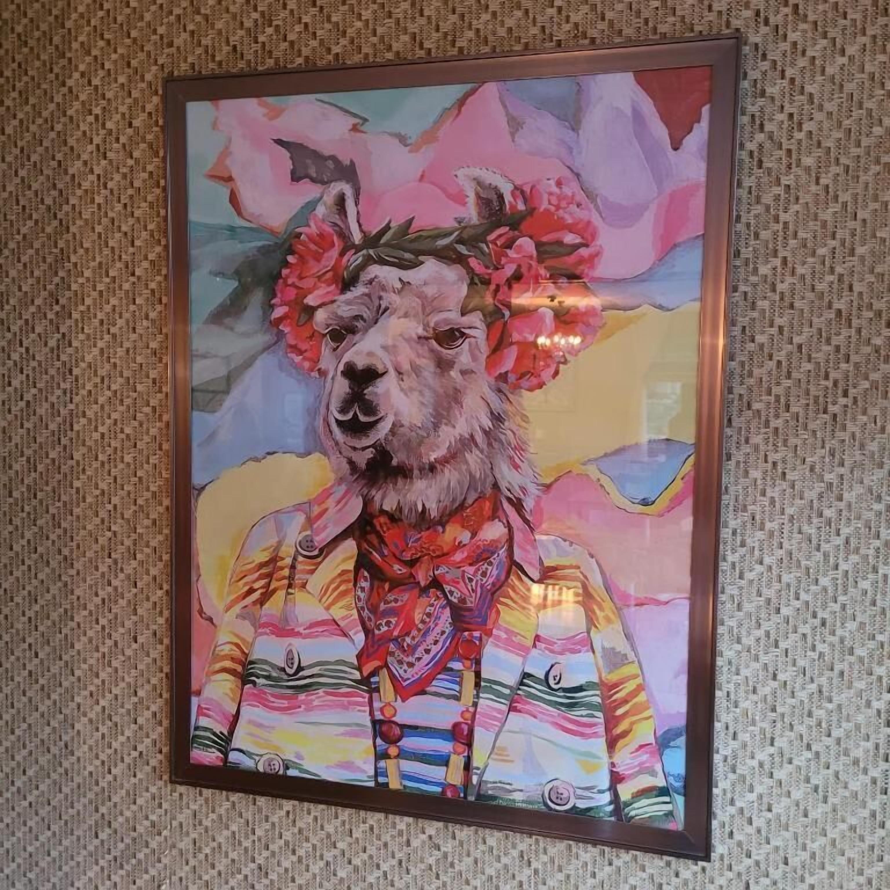 A framed painting of a llama with a floral headdress and colorful clothing.