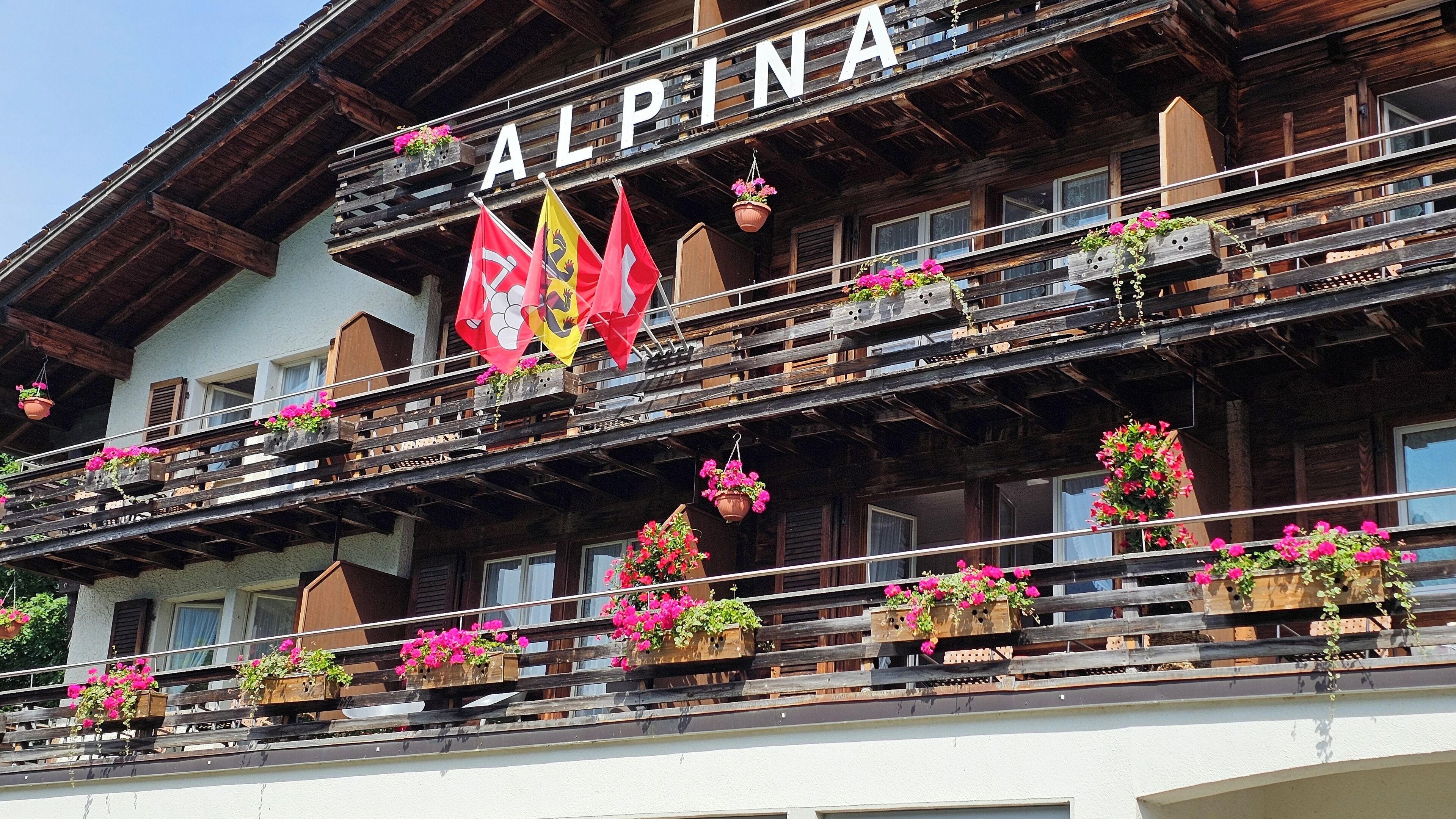 A wooden building with balconies adorned with flower boxes and flags.