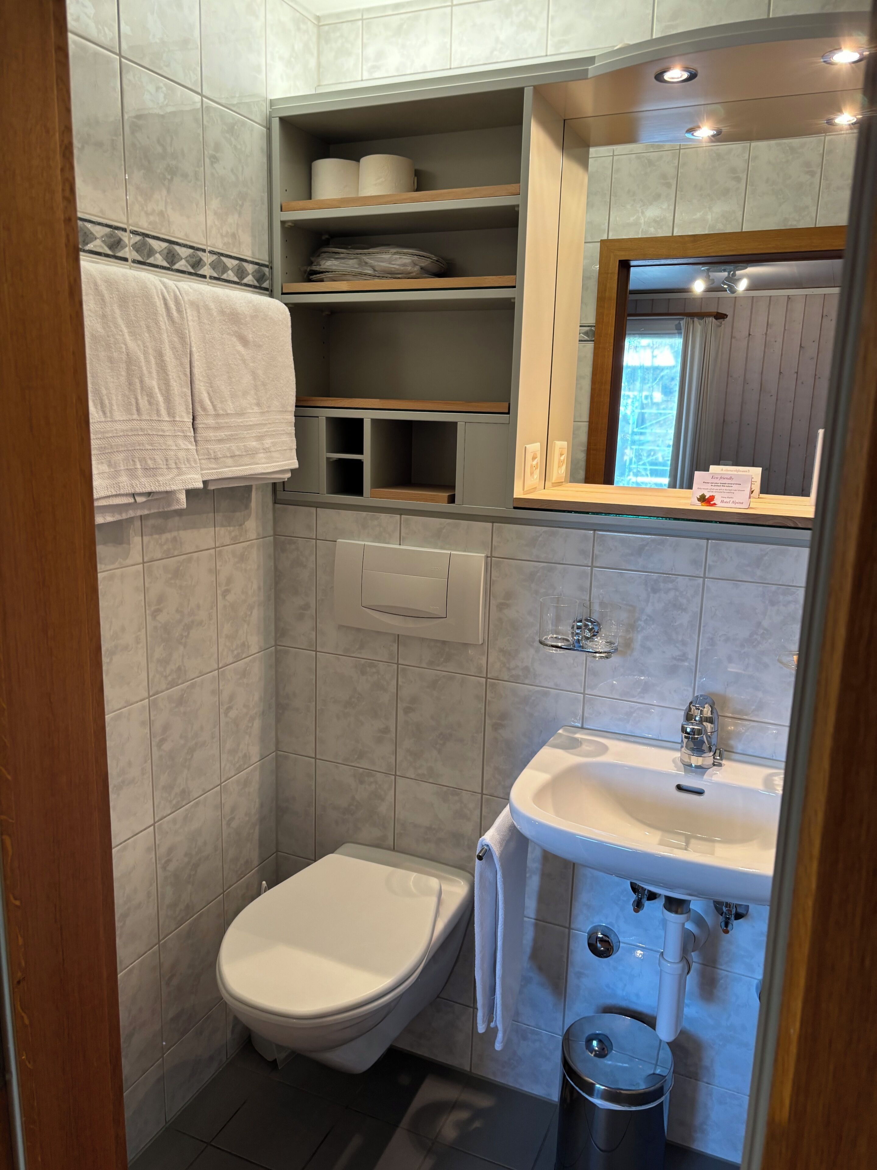 Un baño con inodoro, lavabo y repisas con toallas.