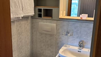 Un baño con inodoro, lavabo y repisas con toallas.