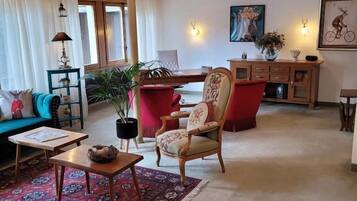 A spacious living room with a chandelier, a red armchair, a sofa, and a coffee table.
