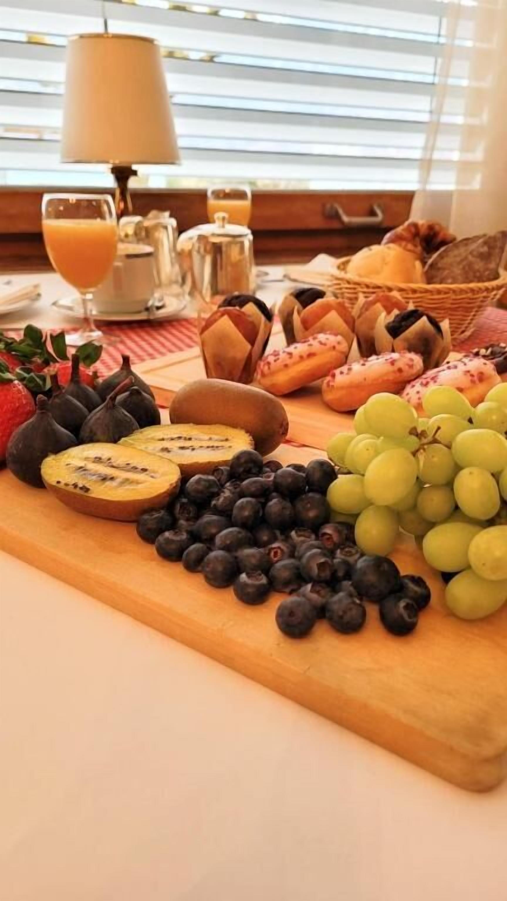 A breakfast spread with fruits, bread, and a coffee pot on a table.