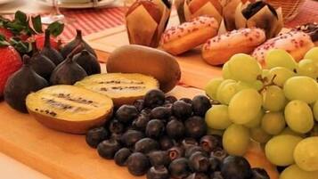 A breakfast spread with fruits, bread, and a coffee pot on a table.