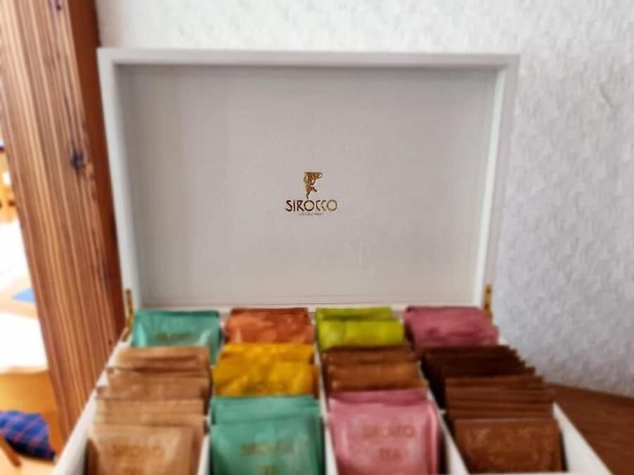 A white box with a logo labeled "SIROCCO" on the lid, containing variously colored chocolate bars.