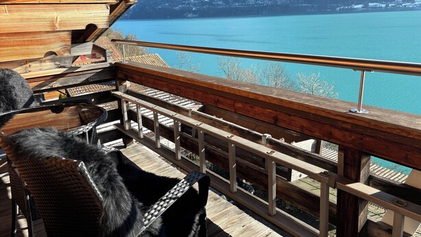 Una terraza de madera con vista a un lago y montañas.
