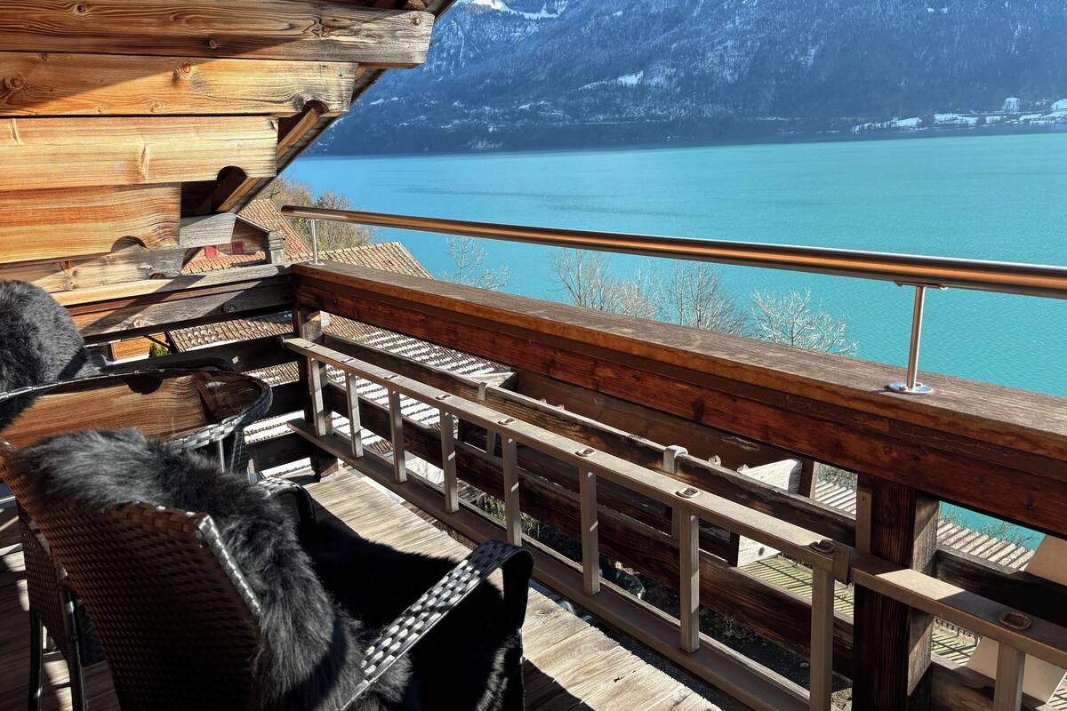 Una terraza de madera con vista a un lago y montañas.