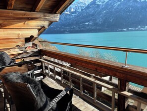 Una terraza de madera con vista a un lago y montañas.
