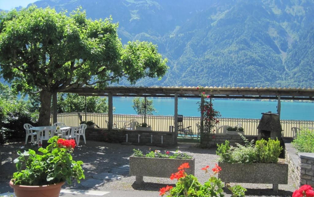 Una terraza con plantas en macetas, muebles de exterior y vistas a un lago y montañas.