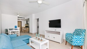 En moderne stue med sofa, sofabord, TV-møbel og en farverig lænestol.