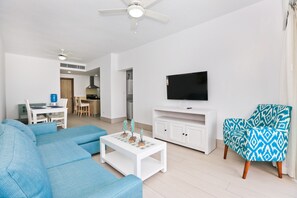 Ein modernes Wohnzimmer mit einer Couch, einem Couchtisch, einer TV-Konsole und einem gemusterten Sessel.