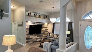 Un salon moderne doté d’un téléviseur à écran plat, d’une cheminée et d’un coin repas.