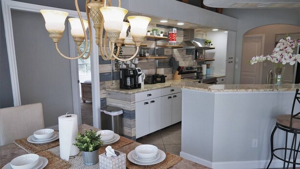 Une cuisine moderne dotée d’un îlot central, de meubles blancs et d’un lustre.