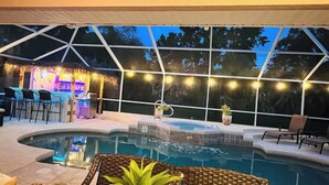 Un espace piscine intérieure doté d’un bar, de coins salon et d’une structure surmontée d’un toit de chaume.