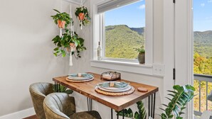 A dining area with a wooden table, two chairs, and a view of a mountainous landscape through a window. - "New Listing" Private Romantic Guest Loft with a VIEW! (Marion)
