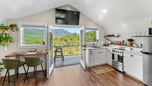 A modern kitchen with white cabinets, a stainless steel stove, and a large window overlooking a forested mountain. - "New Listing" Private Romantic Guest Loft with a VIEW! (Marion)