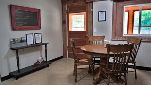A dining area with a wooden table and chairs, a chalkboard menu, and framed documents on the wall. - T's Fish Camp--Crappie Are Biting—Sleeps up to Six (Warsaw)