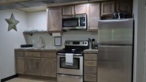 A kitchen with wooden cabinets, a stainless steel microwave, oven, and refrigerator. - T's Fish Camp--Crappie Are Biting—Sleeps up to Six (Warsaw)