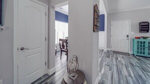 Un pasillo con piso estampado, puertas blancas y un mueble azul turquesa.