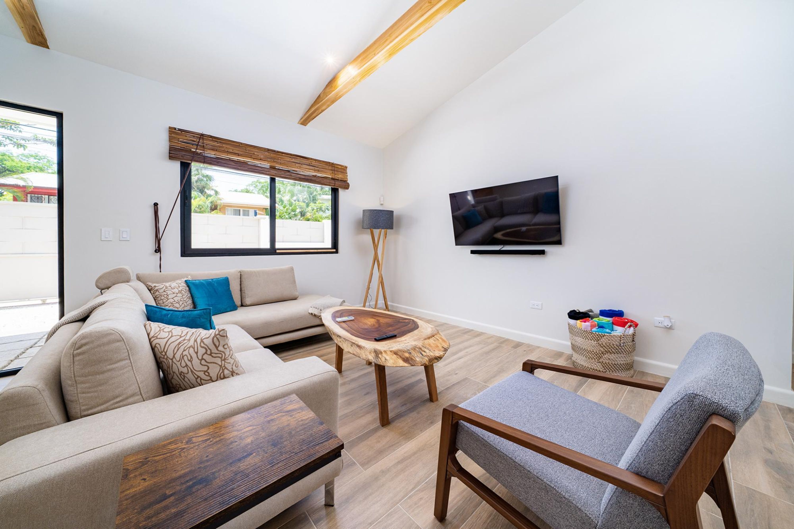 A modern living room with a sofa, a coffee table, a chair, a TV, and a window with blinds.