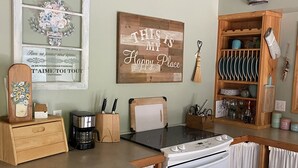 Et køkken med træbordplade, kaffemaskine, komfur og et skilt med teksten "THIS IS MY Happy Place".