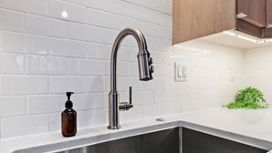 A kitchen with a stainless steel sink, a modern faucet, and white subway tiles on the wall. - Steps To Lake|Garage Parking|Fire Table|Deck|Bikes (Minneapolis)