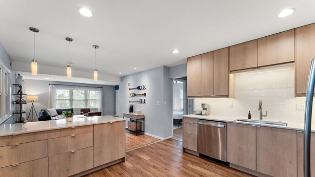 A modern kitchen with wooden cabinets, a central island, pendant lighting, and a dishwasher. - Steps To Lake|Garage Parking|Fire Table|Deck|Bikes (Minneapolis)