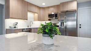 A modern kitchen with wooden cabinets, a stainless steel refrigerator, and a potted plant on the counter. - Steps To Lake|Garage Parking|Fire Table|Deck|Bikes (Minneapolis)