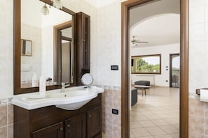 A bathroom with a large mirror, a sink, and a vanity. There is a door leading to a balcony with a view of greenery. - Villa Bella con Piscina by Wonderful Italy (San Vito dei Normanni)