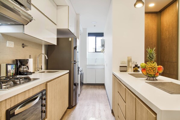 A modern kitchen with stainless steel appliances, a built-in oven, and a coffee maker.
