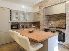 A modern kitchen with a wooden island, stainless steel appliances, and marble backsplash.