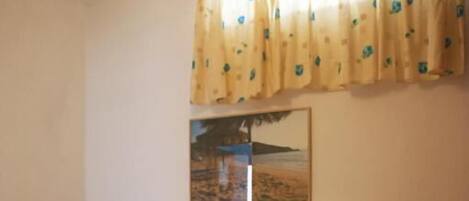 A wooden bed with a headboard, a bedside table, a hanging light fixture, and a window with curtains.