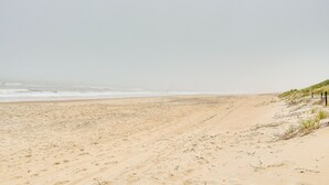 A sandy beach with gentle waves and sparse vegetation. - Nags Head Vacation Rental w/ Hot Tub: Near Beach! (Nags Head)