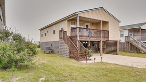 A two-story building with a covered porch and a fenced backyard. - Nags Head Vacation Rental w/ Hot Tub: Near Beach! (Nags Head)