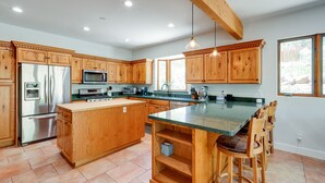 Un'ampia cucina con mobili in legno, elettrodomestici in acciaio inossidabile e una grande isola con sgabelli da bar.