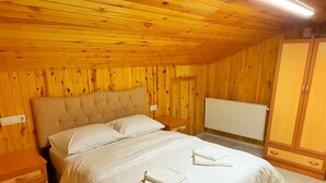 Un dormitorio con paneles de madera, una cama, mesitas de noche y un radiador.
