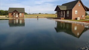 Two wooden cabins by a calm lake with a clear sky.