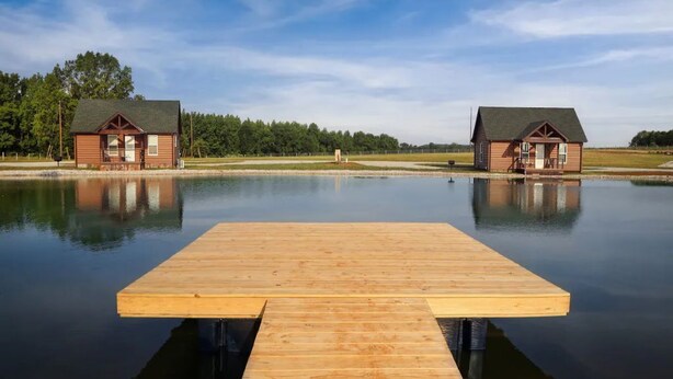 A wooden dock extending into calm water with two cabins on either side.