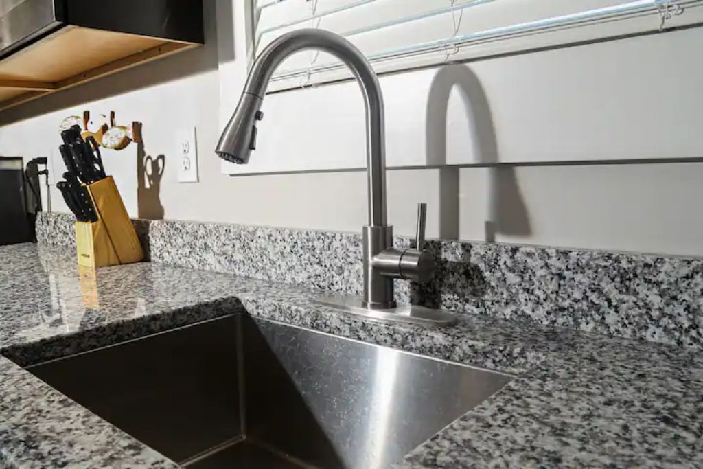 Et køkken med en bordplade i granit, stålvask og moderne armatur.