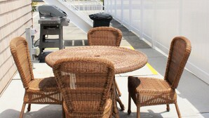 A patio with wicker furniture and a barbecue grill.