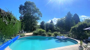 En trädgård med en pool, omgiven av träd och ett staket.