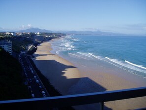 A beach with a road running parallel to it, buildings in the background, and a clear sky. - Studio Front de mer Biarritz vue Exceptionnelle + Garage (BIARRITZ)