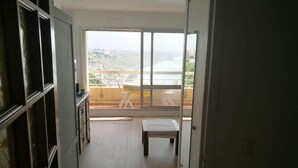 Un corridoio stretto che porta a un balcone con vista sul paesaggio costiero.