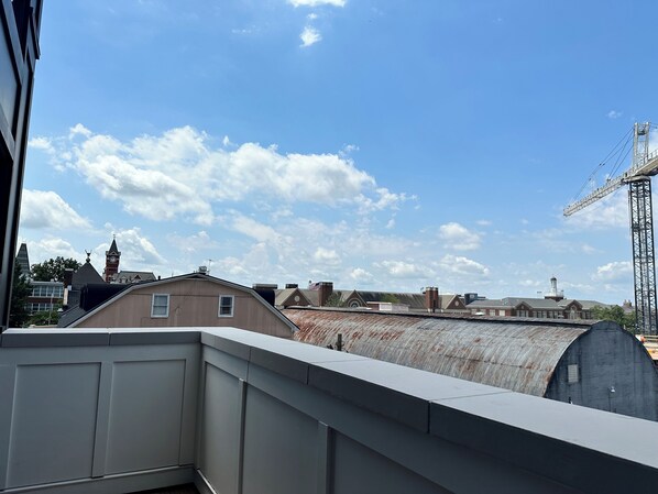 A view of a building with a large, curved metal structure in the background, a clear blue sky, and a crane in the distance. - Luxury 2 Bedroom Above Target in The Godbold Building Downtown Auburn - 201 (Auburn)