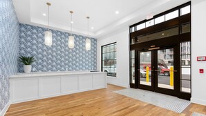 Eine großzügige Lobby mit Holzboden, einem gemusterten Wanddesign und einer Rezeption mit Blumentopf.
