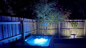 Een hottub met een houten omheining en een plant in pot op de achtergrond.