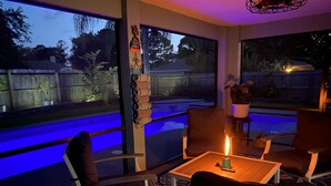 Een knus zithoekje met een tafel, stoelen en een brandende kaars.